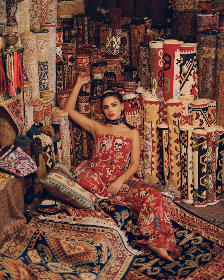 Woman In Jumpsuit Sitting Next To Carpets And Rugs