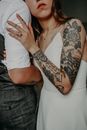 Tattooed Arm of Unrecognizable Bride Clinging to Groom