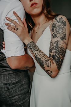 Close-up of a tattooed bride embracing the groom, highlighting wedding attire and unique tattoos.