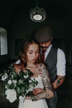 A bride and groom sharing an intimate moment indoors with flowers.
