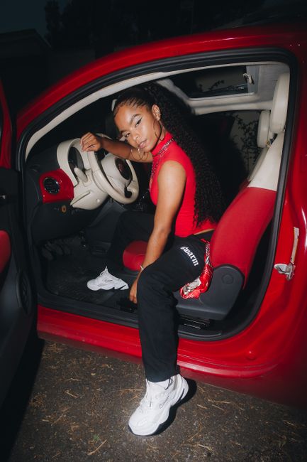 Confident young woman posing stylishly inside a vibrant red car.