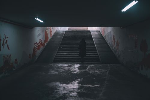 Free Dark urban tunnel with a solitary figure silhouetted on stairs, creating a mysterious ambiance. Stock Photo