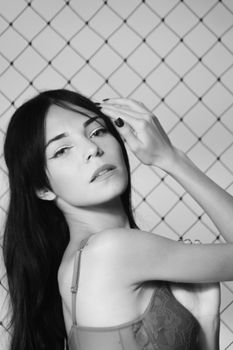 Elegant black and white portrait of a young woman in lingerie posing against a geometric background.