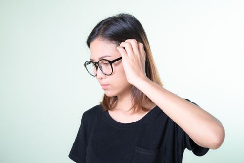 Free Portrait of a young woman wearing glasses, looking thoughtful in a studio setting. Ideal for concept themes. Stock Photo