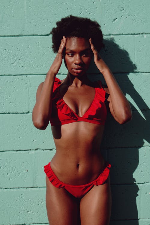 A Woman in Red Bikini Standing in Front of Teal Wall