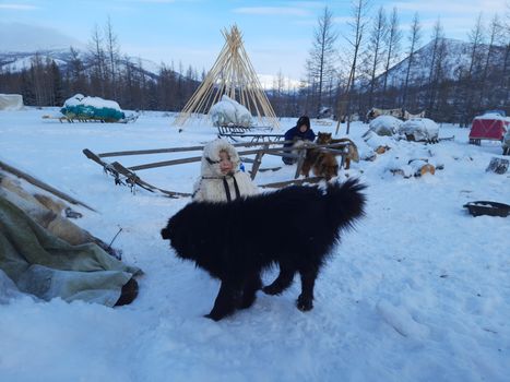 Two children enjoy the snowy outdoors with sled dogs in a winter landscape.