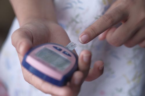 Free An adult using a glucometer to measure blood glucose levels, illustrating personal healthcare management. Stock Photo