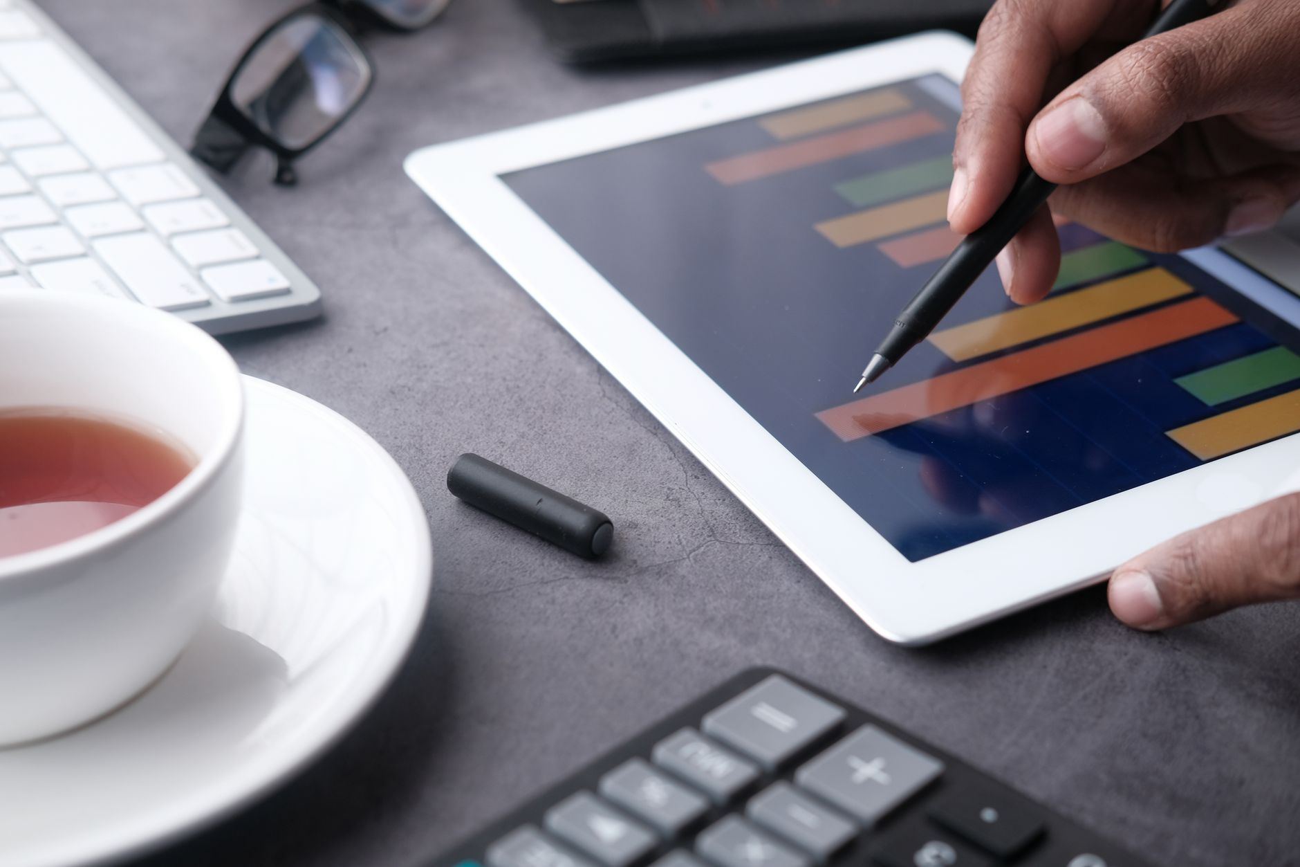 A tablet and stylus on a desk with a signature visible on the screen