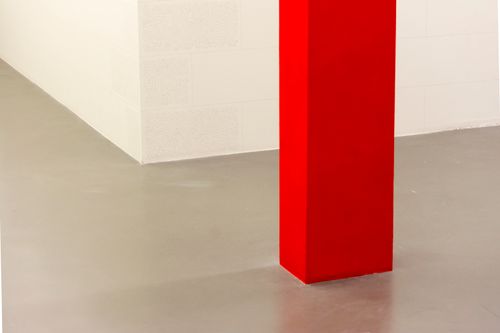 Free A striking minimalist interior featuring a bold red pillar on a smooth concrete floor. Stock Photo