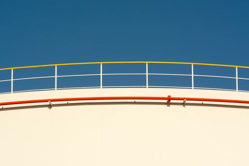 Free Close-up of a white tank against a clear blue sky, featuring yellow railings and red piping. Stock Photo