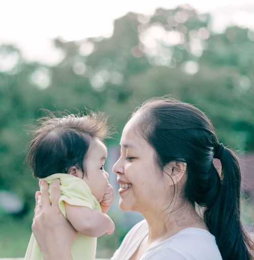 Free A joyful mother shares a loving moment with her baby outdoors, capturing happiness and closeness. Stock Photo