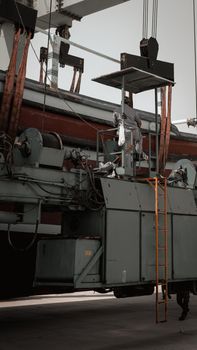 Worker performing maintenance on heavy industrial equipment outdoors.