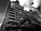 一张黑白照片中，前景是动态的马雕塑，背景是戏剧性的摩天大楼城市场景