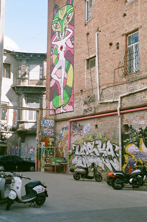 Motorcycles Parked Beside the Brick Building with Graffiti Art