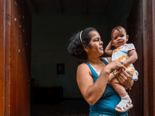 Free A mother lovingly holds her child in a rustic doorway, capturing family warmth. Stock Photo