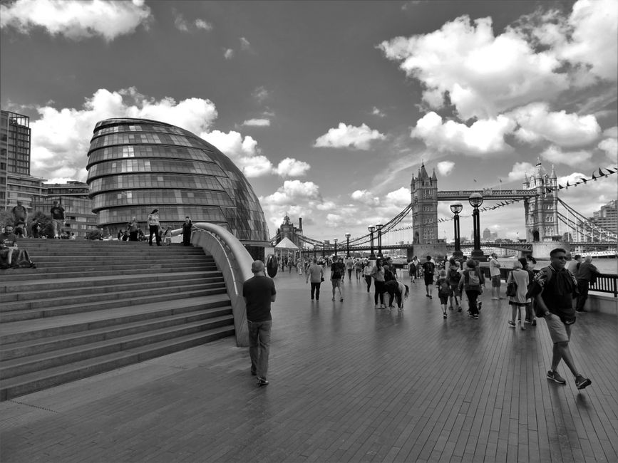 Black and white image of City Hall and Tower Bridge in London, capturing urban life and architecture.