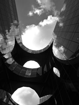 黑白相间的现代摩天大楼在低角度拍摄下映出天空的倒影