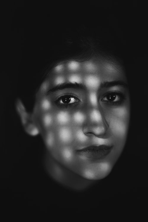 Free Artistic monochrome portrait with dramatic lighting casting shadows on the face. Stock Photo