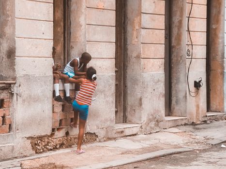Two kids playing on a windowsill in an urban setting, showcasing carefree childhood joy.