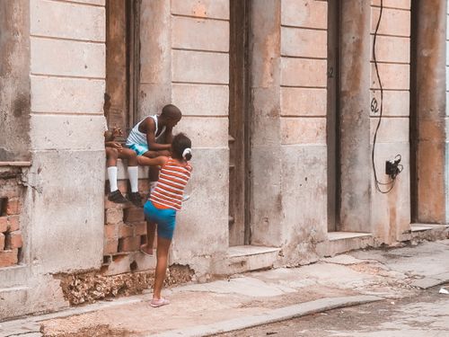 Free Two kids playing on a windowsill in an urban setting, showcasing carefree childhood joy. Stock Photo