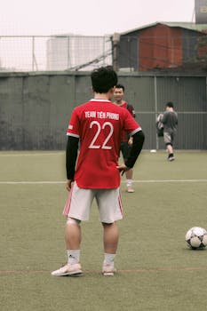 Back view of a soccer player in a red jersey with number 22 on a green field.