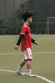 A young male athlete plays soccer on a field in Hanoi, Vietnam, showcasing his skills.