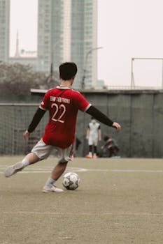 Soccer player in red jersey prepares to kick the ball on an outdoor field.