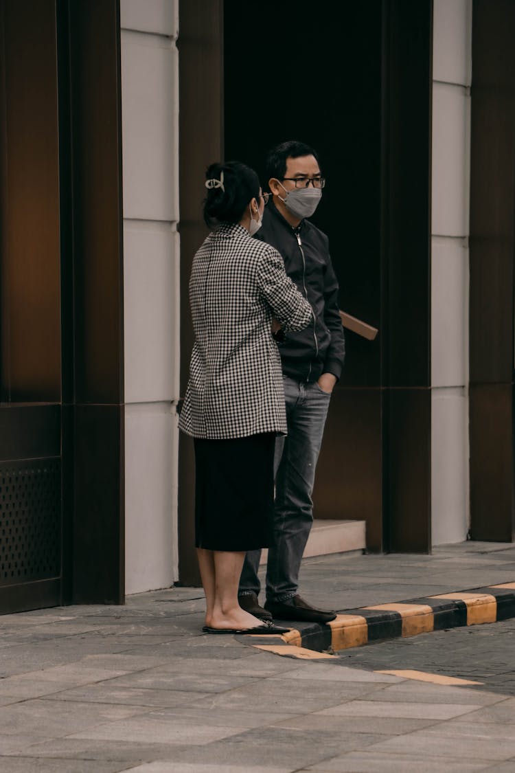 A Man And Woman Standing On The Street