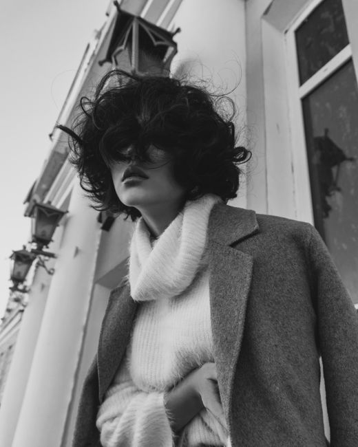 Elegant black and white portrait of a woman in a turtleneck and coat.