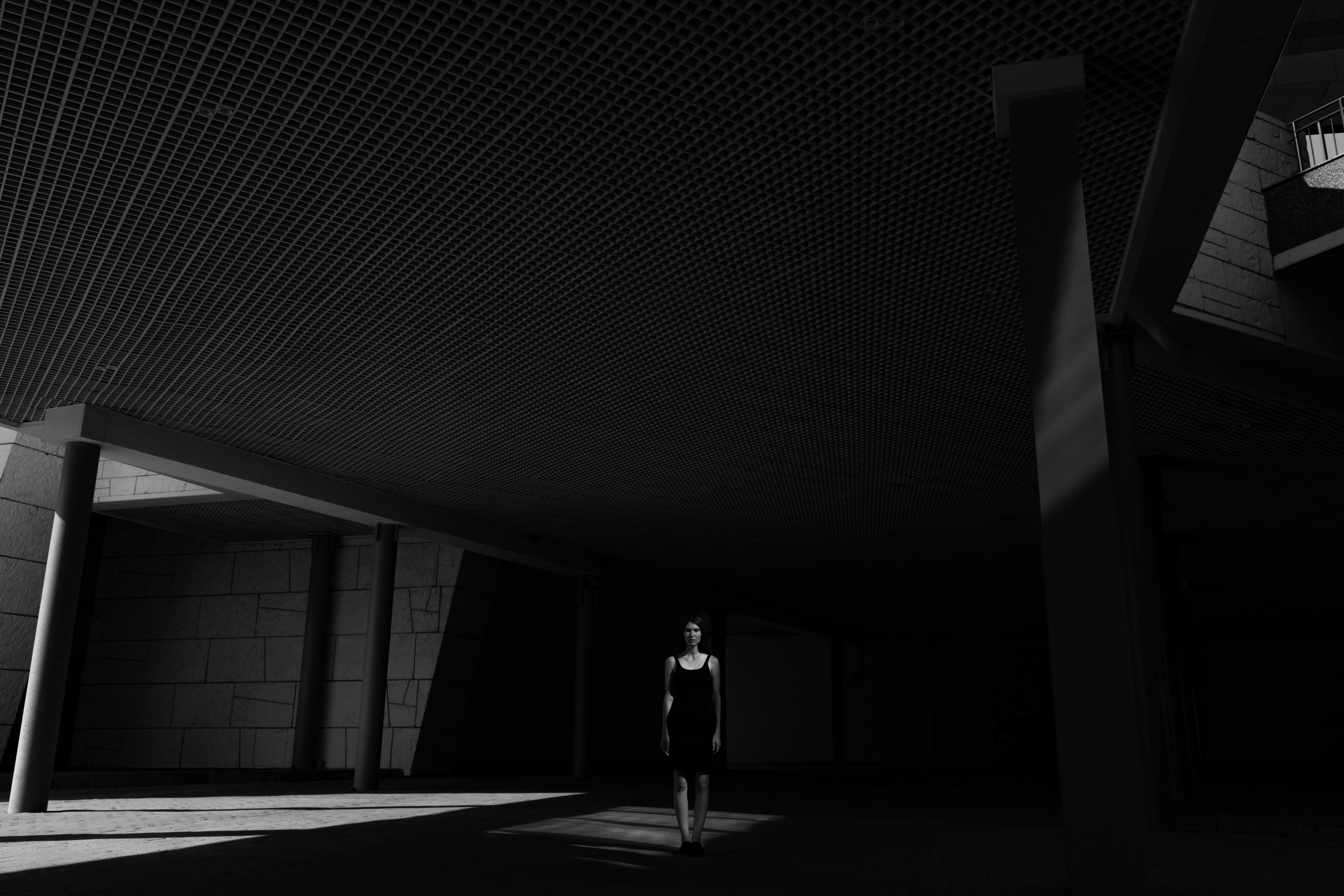 Silhouetted woman walks through a dark urban setting with dramatic lighting and shadows.