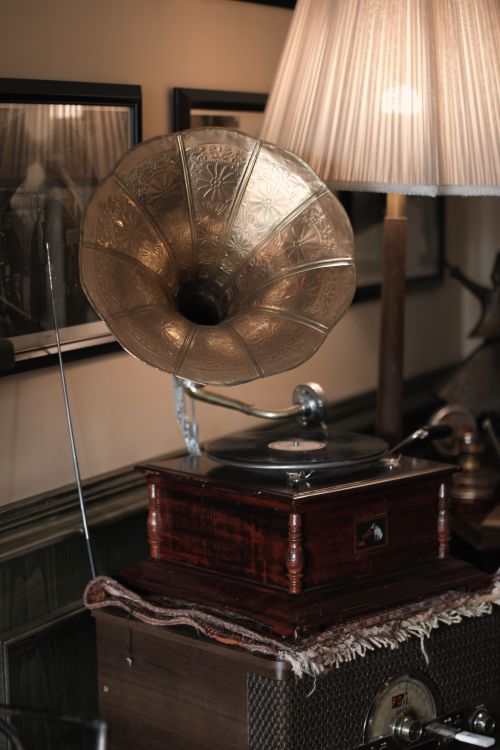 Free Warm and classic interior scene featuring a vintage gramophone and a softly lit lamp. Stock Photo