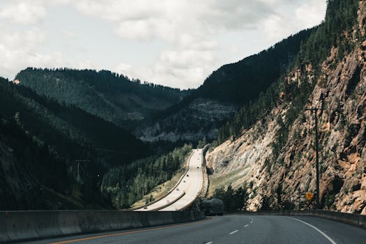 Dramatic mountain highway view in Canadian Rockies, surrounded by lush forests.