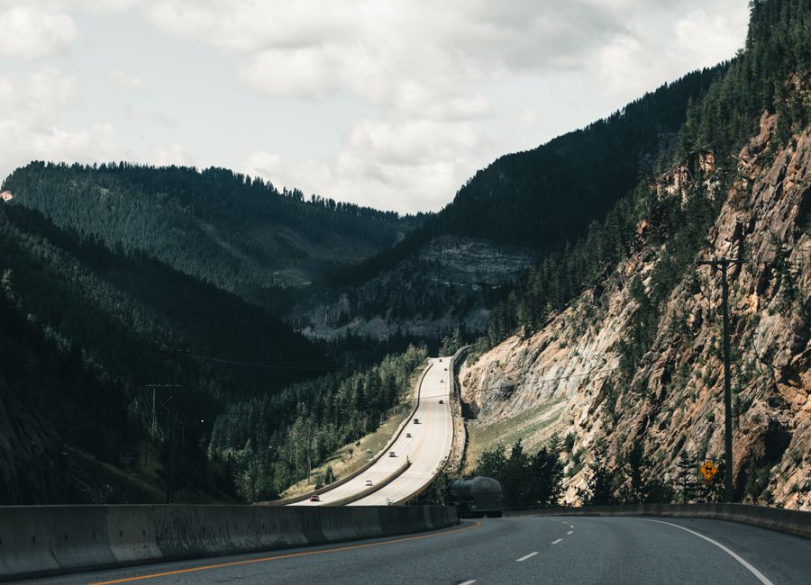 Dramatic mountain highway view in Canadian Rockies, surrounded by lush forests.