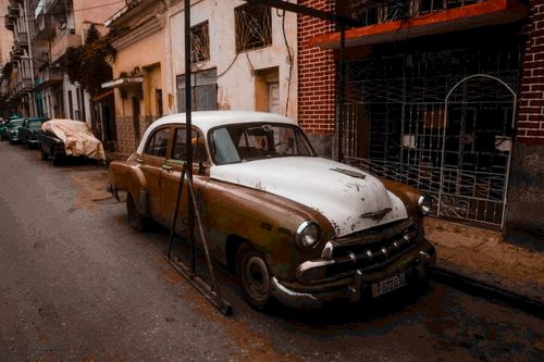 Free Classic vintage car parked on a narrow street in Havana, showcasing retro Cuban architecture. Stock Photo