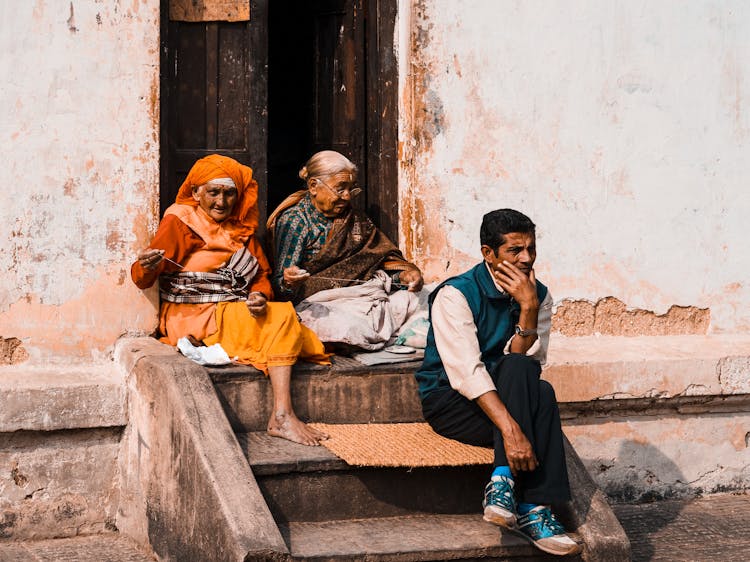 Man And Women Sitting On House Stairs