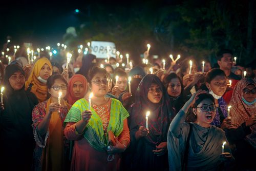 Free A group of South Asian women holding candles at a peaceful nighttime protest for social justice. Stock Photo