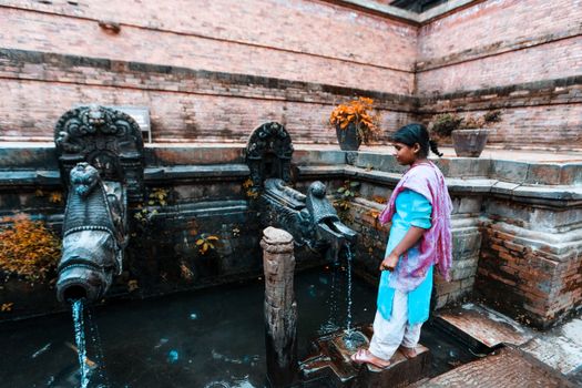 Woman performing ritual at an ancient temple fountain, reflecting cultural heritage.