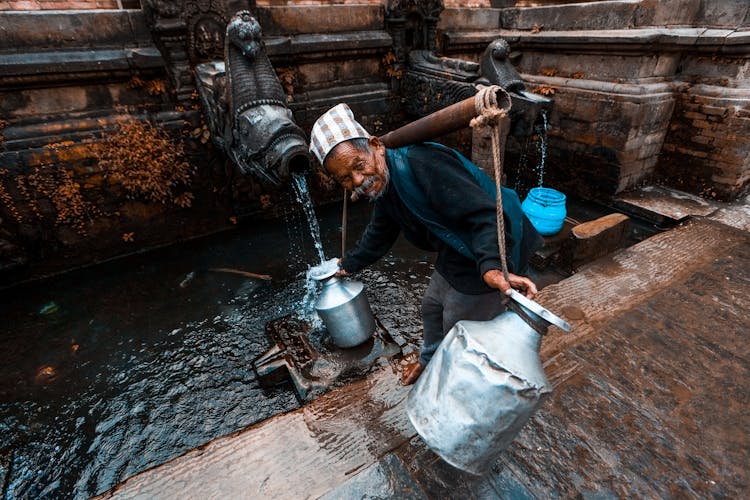 Man Pouring Water From Well