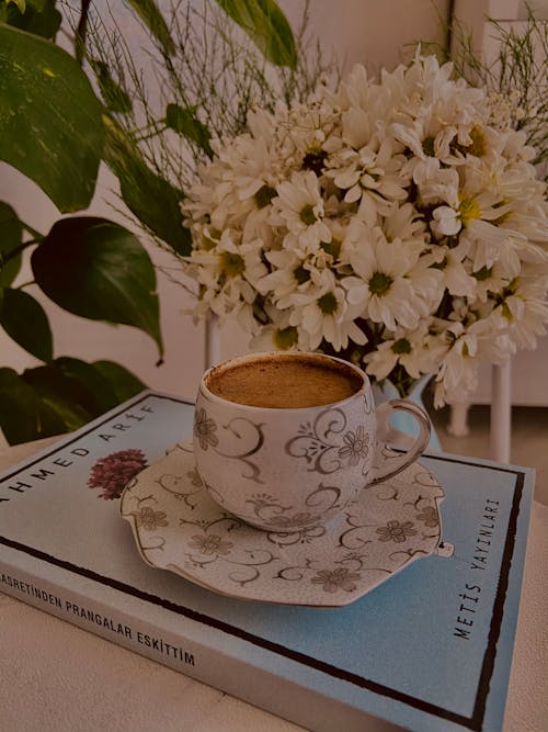Free Coffee Drink on Top of Book beside White Flower Bouquet  Stock Photo