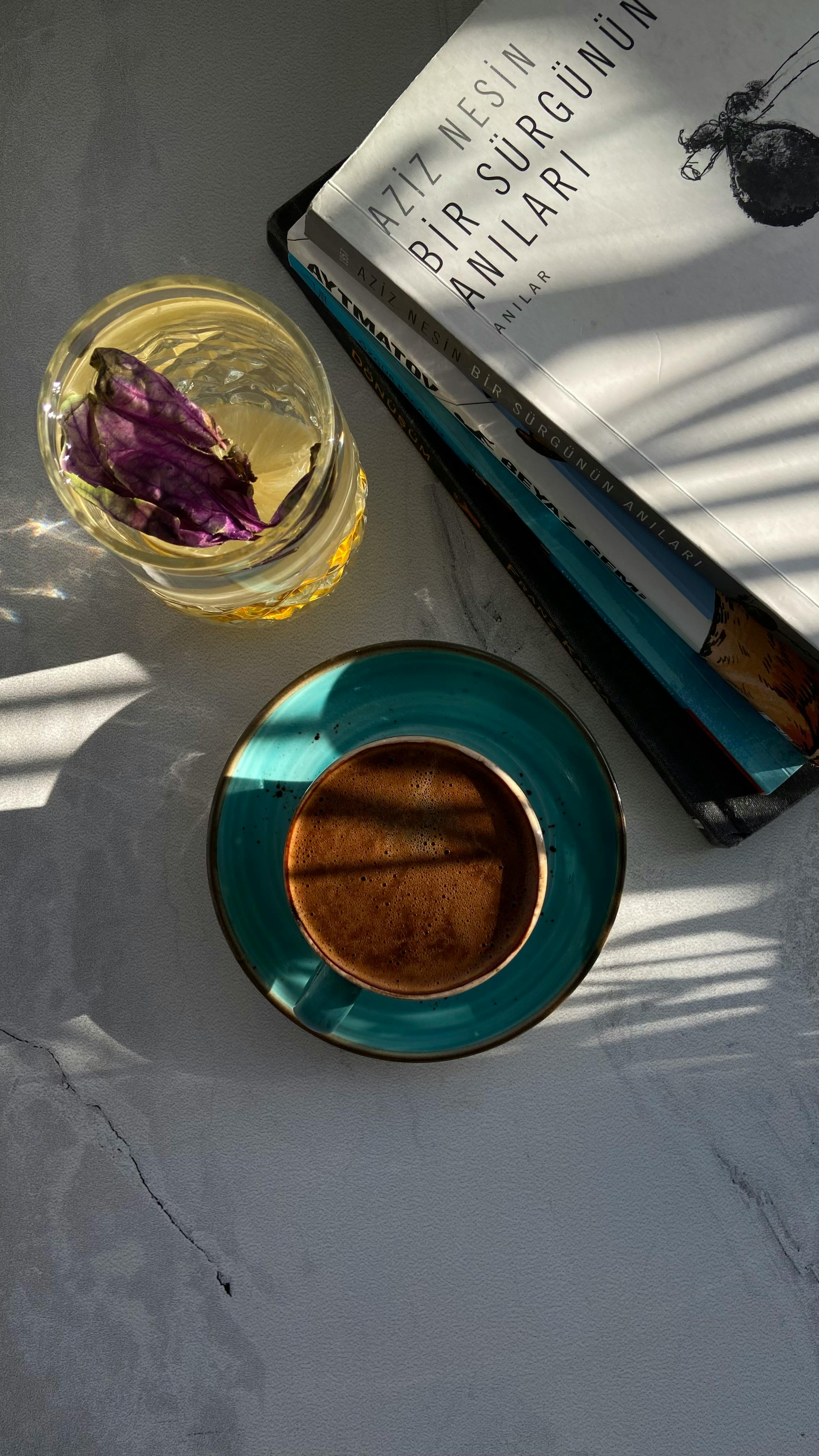 Free Flat lay of coffee, book, and herbal tea on a sunlit surface, evoking a cozy reading atmosphere. Stock Photo