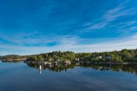 清澈的蓝天映照在美丽的湖畔风景中，四周环绕着树木和房屋