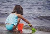 一个年轻女孩在海边玩水桶和铲子，享受夏日时光