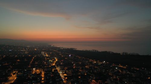 Free Stunning aerial cityscape at dusk featuring city lights and coastline under a colorful sky. Stock Photo