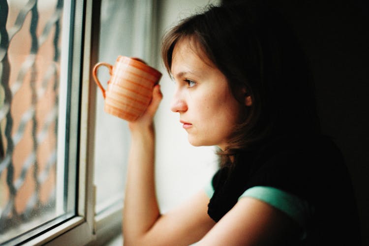 Woman With Mug Looking Through Window