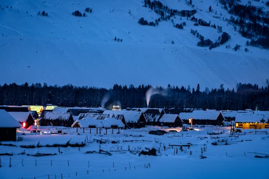 Charming winter village under a blanket of snow, lit up on a cold night in the mountains.