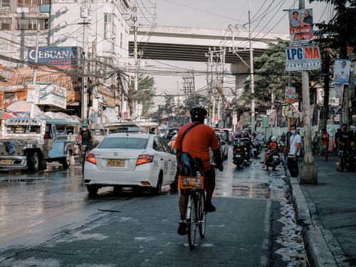 Free A cyclist rides through a bustling street in Manila, surrounded by cars, motorcycles, and jeepneys. Stock Photo