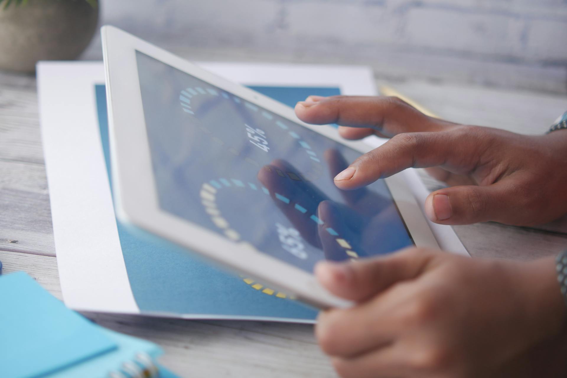 Hands interacting with a tablet, showcasing modern touchscreen technology in an indoor setting.