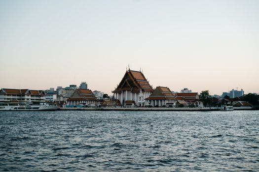 Serene view of Wat Kanlayanamit Woramahawihan by the Chao Phraya River in Bangkok, Thailand.