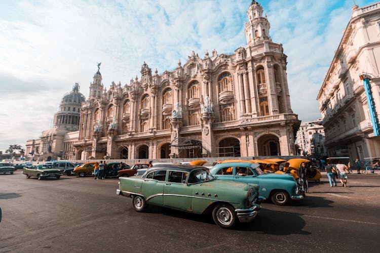 Vintage Cars Parked In Front Of Beige Baroque Building In Havana, Cuba