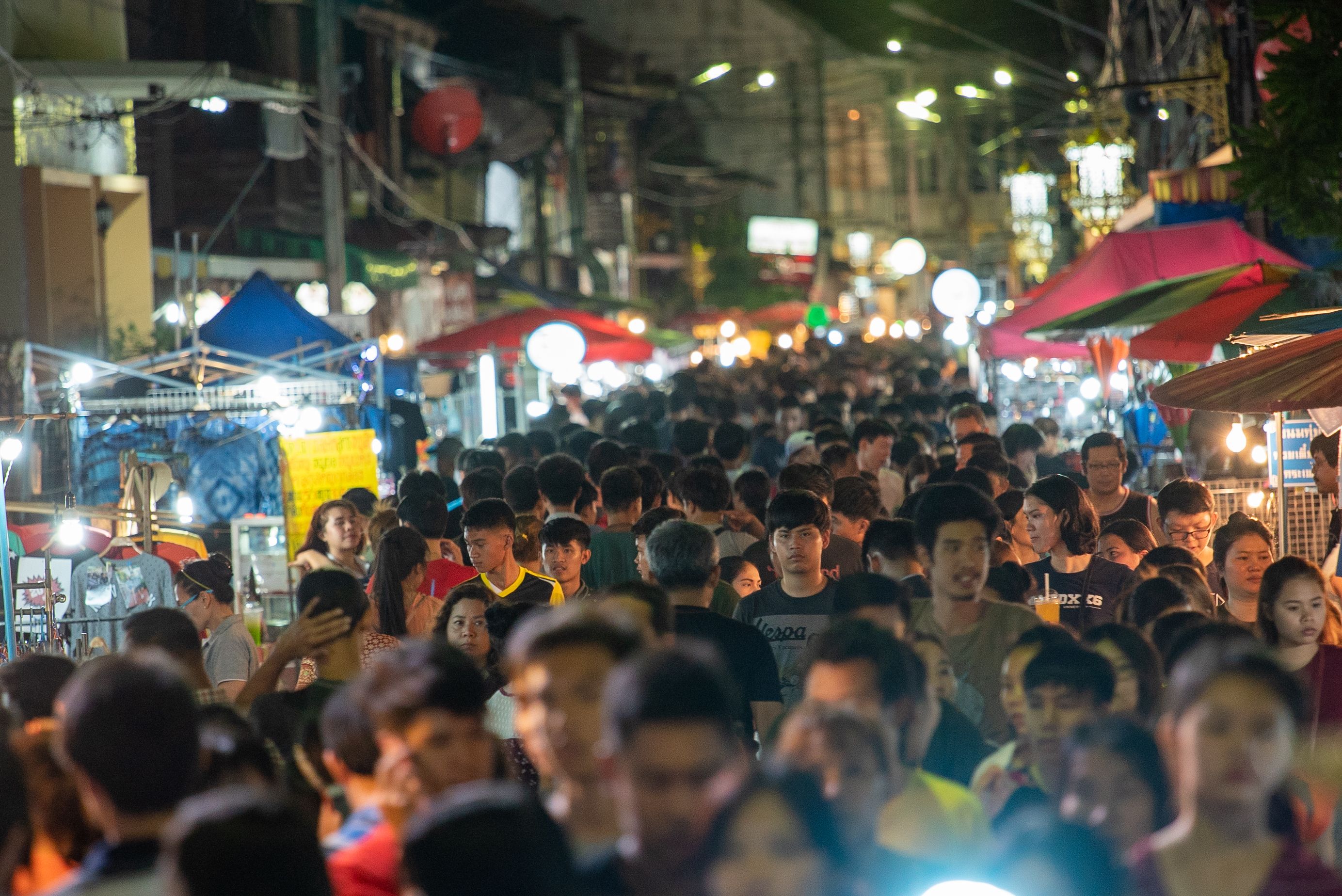 Lively night market scene with a crowded street filled with people and vibrant stalls.